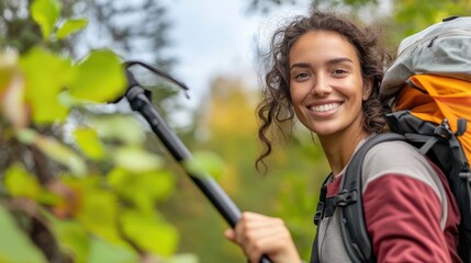 Obraz premium Smiling young woman enjoying outdoor adventure with backpack and hiking pole