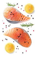 Fresh salmon steaks, spices and lemon slices falling on white background