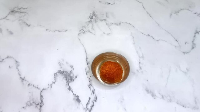 Hand adds spices to small bowl in Indian kitchen