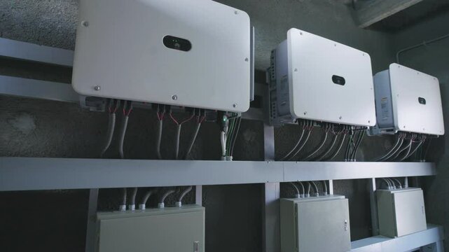 Several solar inverters are converting direct current into alternating current, hanging on a wall inside a building