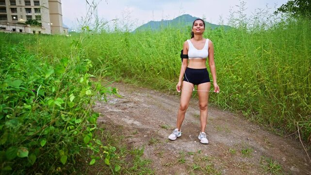 Woman in sports bra pauses on dusty trail