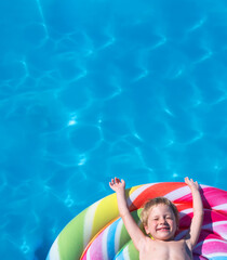 child lies on a colorful inflatable mattress in the swimming pool