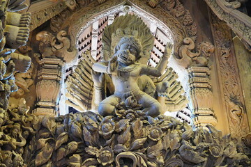 A close-up view of an intricately carved wooden deity sculpture inside the Sanctuary of Truth in Pattaya, Thailand. 
