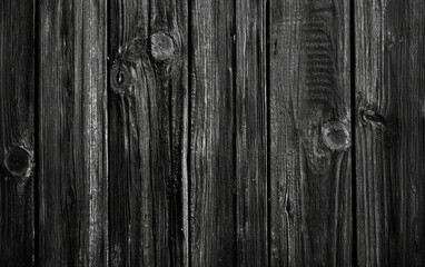 A close-up of a wooden surface showcasing its dark, grainy, and textured appearance, with visible weathered and rustic details.	
