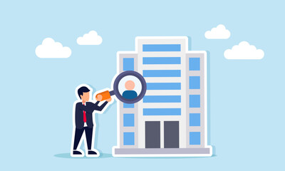 Businessman using magnifying glass to examine candidate profile from company building illustrating executive recruitment process