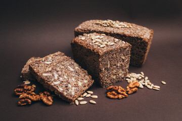 Homemade bread cut into slices with sunflower seeds and nuts close-up, natural light with copy space on brown background