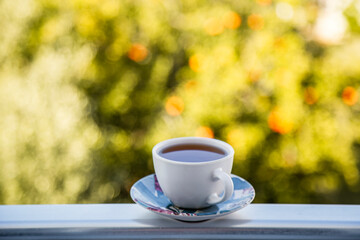 Cup of tea on the balcony with a vibrant garden backdrop