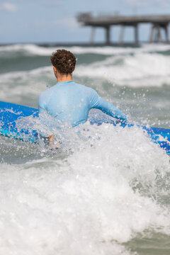 Teenage Boy in Blue Rash Guard Entering Waves for Surf Lesson