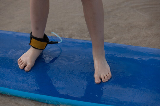 Child Standing on Blue Surfboard with Ankle Leash learn to surf