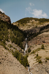 Mountain waterfall flowing through pine forest valley