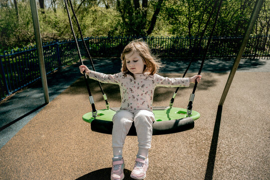 Toddler girl on swing on the playground. Education, actitvity outdoor