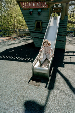 Toddler girl on slide, outdoor playground