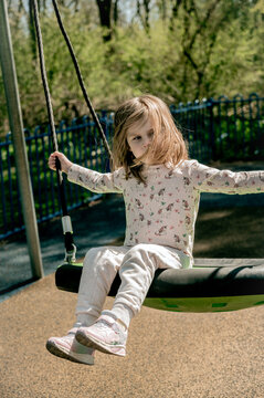 Sad toddler girl on swing, playground. Education, activity outdoor