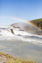 Powerful waterfall with rainbow under a clear blue sky