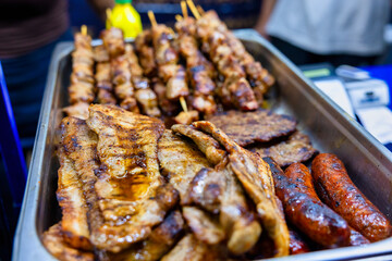skewers, pork belly and sausages grilled over charcoal .