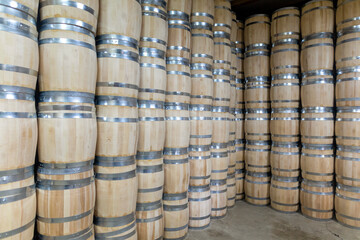 Rows of wooden barrels are neatly stacked in a storage area