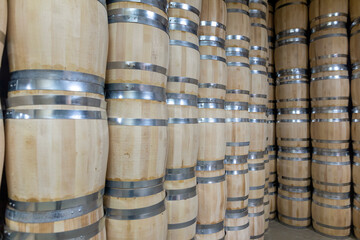 Rows of wooden barrels are neatly stacked in a storage area