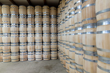 Rows of wooden barrels are neatly stacked in a storage area