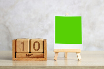 Wooden perpetual calendar showing may 10th with green screen photo frame