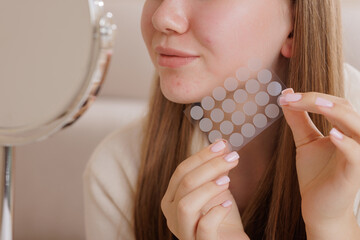 Closeup of girl applying acne patch for skincare, showing hydrocolloid spot treatment for pimples.