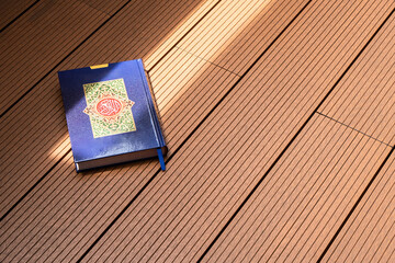 Holy Al Quran with written arabic calligraphy with natural daylight on wooden background
