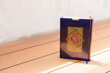 Holy Al Quran with written arabic calligraphy with natural daylight on wooden background