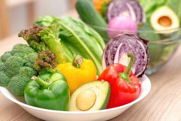 Close up of a white bowl filled with fresh broccoli, bell peppers, avocado, and lettuce, Healthy Eating.