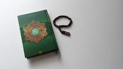 Obraz premium Holy Quran with Arabic calligraphy with wooden beads or tasbih on white background