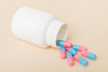 different drugs and health supplement pills poured from a medicine bottle health care and medical top view on colored background