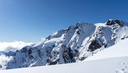 Fototapeta premium Majestic snow covered mountain peaks rise dramatically against clear blue sky, showcasing beauty of nature. pristine white snow glistens in sunlight, creating serene and breathtaking landscape