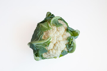 Whole, raw head of Cauliflower with green leaves. Close up studio shot, isolated on white, no people