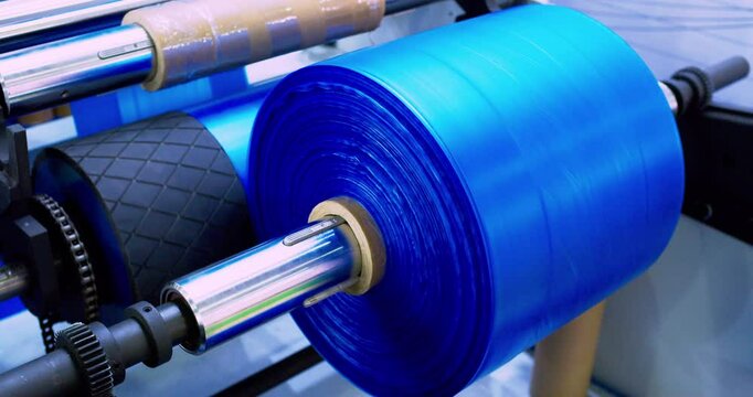 Plastic film moves along the production line. Working packaging production machine. Technological process of household plastic production.