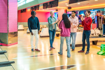 Happy friends congratulating each other after bowling game in entertainment center