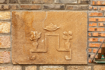 An ancient bas-relief depicting various flowers is mounted into a brick wall