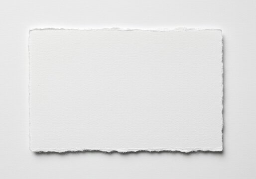 A blank white paper sheet with deckled edges sits on a white surface in a simple studio shot