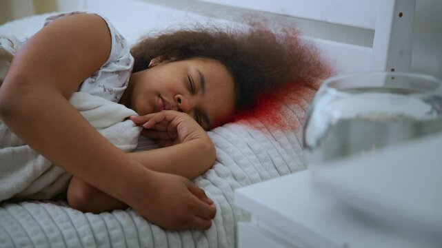 Peaceful young girl sleeping soundly in bed, unconscious of growing red blood stain gradually spreading across pillow from her hair