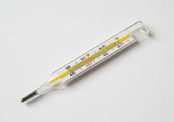 Glass mercury thermometer showing a normal body temperature on a white surface