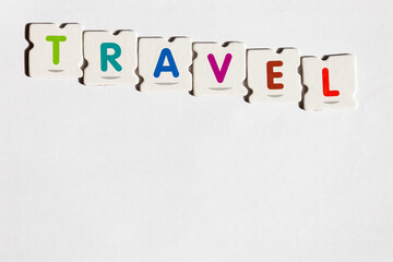 TRAVEL – Word assembled from colorful puzzle letters on white background