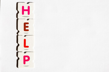 HELP – Word assembled from colorful puzzle letters on white background
