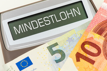 15 Euro liegen auf einem Taschenrechner mit der Aufschrift Mindestlohn im Display