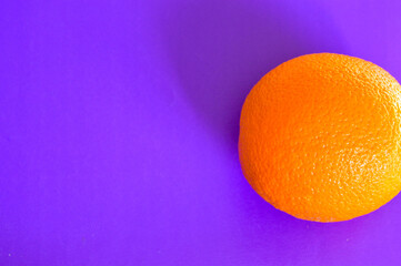 Fresh orange on vibrant purple background. Minimalist pop art style, healthy food concept, bold color contrast, creative composition, modern design trend.