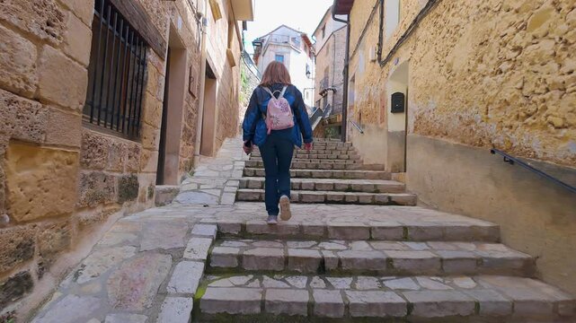 Tourist woman strolling through the steep streets of the picturesque village of Beceite, Teruel, Aragon.