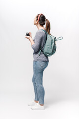 Young woman with a backpack on her shoulders waiting and holding a camera