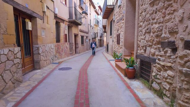 Tourist woman strolling through the streets with stone arches in the medieval village of Beceite, Teruel, Spain.