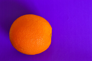 Fresh orange on vibrant purple background. Minimalist pop art style, healthy food concept, bold color contrast, creative composition, modern design trend.