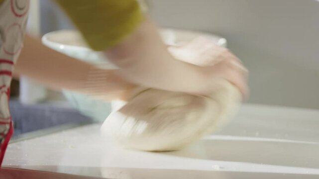 Gentle kneading of bread dough in natural light creates a calm, homely kitchen moment. A close-up shot.