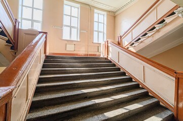 Ornate indoor staircase with vintage design, featuring stone steps, painted wood, and decorative ceiling details.
