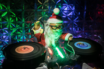 Christmas and New Year club concept. Dj mixer with headphones on snow. Santa Claus is mixing on turntable. Creative miniature