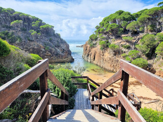 Looking Through Wallagoot Gap From a Sandy Beach to the Southern Ocean. High Tree Covered Cliffs Above Crashing Waves. Taken at Wallagoot Gap in Bournda National Park, New South Wales, Australia