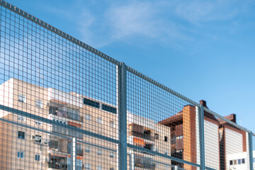 Urban skyline behind mesh fence on a sunny day.